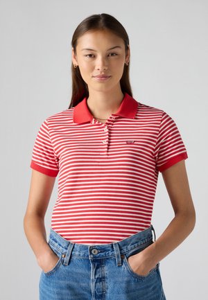 Rood-witte gestreepte polo met een rode kraag, korte mouwen en een klein logo op de borst, gecombineerd met blauwe high-waisted denim shorts.
