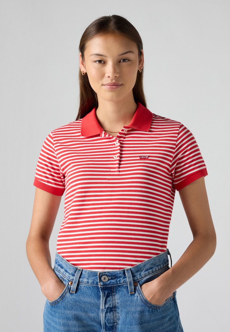 Polo à rayures rouges et blanches avec un col rouge, des manches courtes et un petit logo sur la poitrine, associé à un short en denim bleu taille haute.