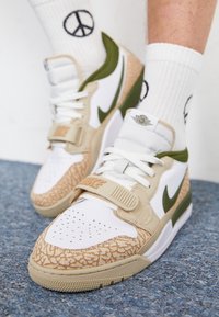 Nike sneakers featuring a white mesh upper, tan leather accents with embossed texture, green details, and a Velcro strap.