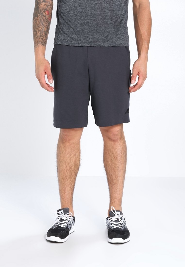 Pantalones cortos atléticos grises hechos de material liviano, con una cinturilla elástica y un pequeño logo en el lado inferior izquierdo. Zapatillas negras con cordones blancos.