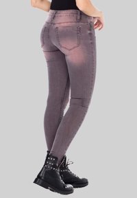 Jean skinny de couleur mauve avec un effet délavé, doté de cinq poches et d'une coupe ajustée. Associé à des bottes de combat noires avec des clous.