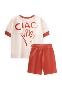 Lasten asu, jossa on kerma-valkoinen lyhythihainen paita, jossa on punainen "CIAO" -printti ja käden grafiikka. Asua täydentävät teksturoidut punaiset shortsit.