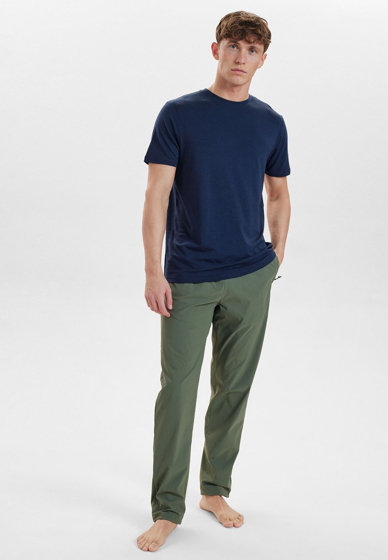 Mørkeblå kortærmet t-shirt parret med olivengrønne tapered bukser. T-shirten har en rund halsudskæring, og bukserne har sidelommer.