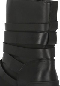 Stivaletto nero alla caviglia con cinturini in pelle sovrapposti e finitura liscia. Punta leggermente arrotondata e suola robusta dal design minimalista.