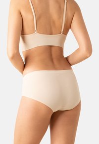 Ensemble de soutien-gorge et culotte beige sans couture en matériau doux, avec des bretelles fines et ajustables et un design lisse et simple.