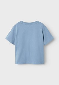Lyseblåt bomulds T-shirt med korte ærmer, rund halsudskæring og subtile prikker i stoffet. Ingen synlige lukninger eller logoer.