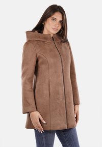 Cappotto in finta suede marrone con cappuccio, caratterizzato da una chiusura a zip, maniche lunghe e cuciture curve per una vestibilità strutturata.