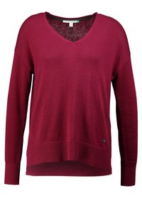 Vinröd stickad tröja med V-ringning, långa ärmar, ribbade mudd och fåll. Har en liten logodetalj längst ner till vänster. Mjuk textur.