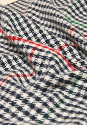 Weicher Wollstoff mit schwarz-weißem Hahnentrittmuster, versehen mit roten und grünen Karostreifen, in Nahaufnahme gefalteter Ansichten.