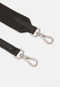 Sangle en tissu noir avec des accents en cuir lisse, dotée de crochets à pression en métal argenté à chaque extrémité pour fixation. Détail de surface texturée visible.