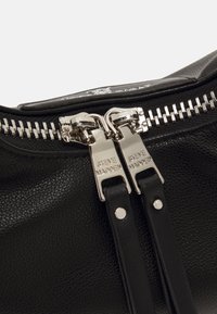 Zwarte leren tas met een dubbele ritssluiting en hardware in zilverkleur. De textuur is geribbeld, met gladde accenten.