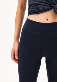 Navy blauwe leggings met een hoge tailleband, gemaakt van een gladde, rekbare stof; voorzien van een subtiele naad langs de taille en zijkant.