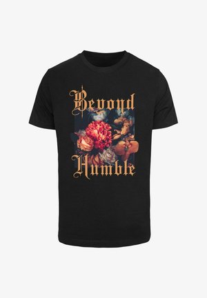 Sort T-shirt med et grafisk design af farverige blomster og teksten "Beyond Humble" i prangende orange skrifttype. Korte ærmer, normal pasform.