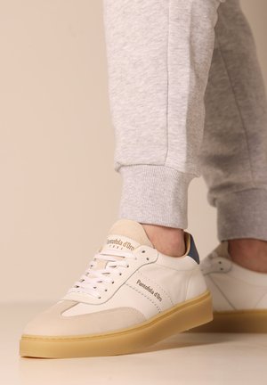 Sneaker bianche in pelle con dettagli in suede beige e tallone blu navy, dotate di chiusura con lacci e suola in gomma.