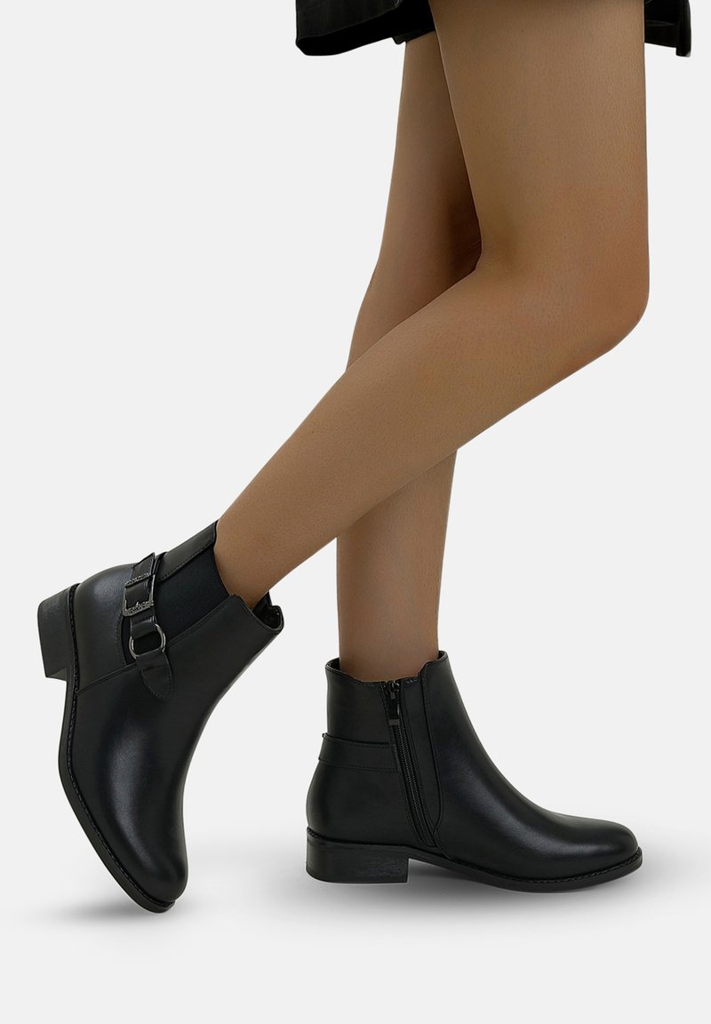 Botas negras hasta el tobillo hechas de cuero suave, con cierre de cremallera lateral, detalle de hebilla y un tacón bajo de bloque. Diseño sencillo con puntera redondeada.