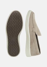 Beige suede slip-on shoes with a rounded toe, featuring a textured brown rubber sole and white accents. Includes logo detail on the side.
