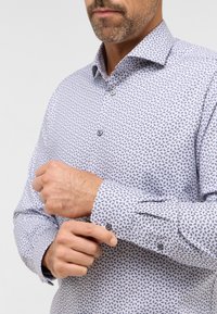 Himmelblaues, gemustertes Hemd mit dunklen Blattmotiven, Button-Down-Kragen und kontrastierenden Knöpfen an den Manschetten. Baumwollstoff, taillierte Passform.