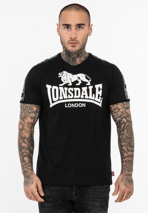Čierne bavlnené tričko s bielym logom "LONSDALE" a grafikou leva na prednej strane, s kontrastnými detailmi na pleciach a krátkymi rukávmi.