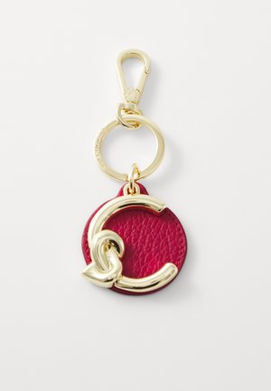 Red leather keychain with a gold metal clasp. Features a circular design with a prominent gold logo accent and textured surface.