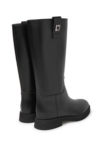 Stivali neri al ginocchio realizzati in pelle liscia con suola piatta. Presentano un accento metallico rettangolare vicino alla parte superiore. Design semplice con texture senza cuciture.