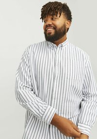 Long-sleeve button-down shirt featuring white fabric with thin gray vertical stripes, a collar, and a chest pocket. Soft texture.