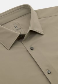 Beige overhemd met lange mouwen, gladde stof, met knoopsluiting, twee knopen aan de voorkant, merklabel zichtbaar. Eenvoudig ontwerp zonder patronen.