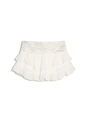 Mini-jupe blanche à volants superposés avec une ceinture en dentelle à œillets.