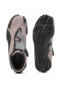 Puma-Sneaker mit einem hellrosa Mesh-Obermaterial, schwarzen Akzenten, verstellbaren grauen Riemen und strukturierten schwarzen Gummisohlen mit Stollen.