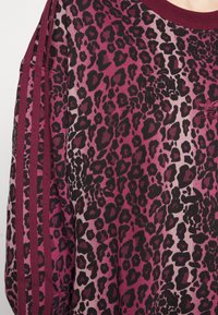 Długi rękaw top w panterkę w odcieniach różu i czerni, z ryflowanym dekoltem i trzema paskami na rękawach.
