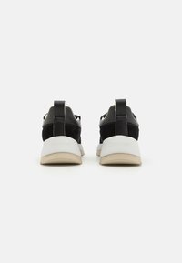 Czarne sneakersy z połączeniem gładkiej i zamszowej tekstury, z białą podeszwą środkową, uchwytem oraz subtelnym logo na pięcie.