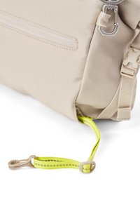 Beige Stoffrucksack mit strukturierter Oberfläche, ausgestattet mit einer seitlichen Reißverschlusstasche und einem kontrastierenden, lebhaft gelben Gurt mit Schnallenbefestigung.