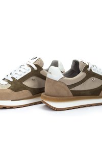 Sneakers atletici beige e verde oliva realizzati in materiali scamosciati e in rete, con lacci bianchi e una suola in gomma caratterizzata da un motivo di battistrada marrone chiaro.