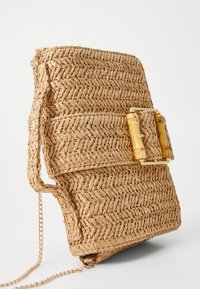 Borsa in paglia intrecciata di colore beige neutro, con un design piatto, fibbia dorata e una catena per il trasporto.