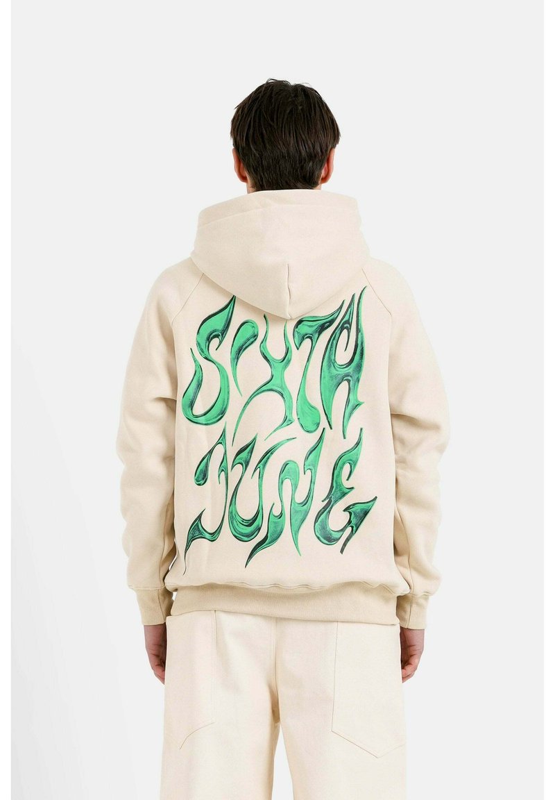 Felpa beige con cappuccio caratterizzata da una grafica verde sul retro, con un motivo di caratteri fluido e ondulato. Tessuto morbido con vestibilità rilassata.
