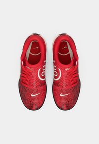 Tenis Nike vermelhos com logótipos brancos e um padrão de pele de cobra, vistos de cima sobre um fundo branco.