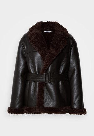 Veste en cuir noir avec doublure en peau de mouton brun foncé, large col, et ceinture assortie avec boucle rectangulaire.