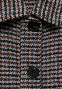 Wollmantel mit Hahnentrittmuster in Blau, Braun und Grau. Sichtbarer schwarzer Kunststoffknopfverschluss und Kragendetails.