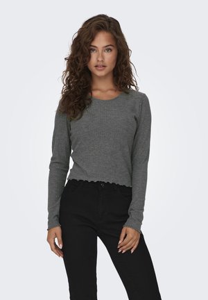Top corto gris de manga larga con textura acanalada y dobladillo con volantes. Combinado con pantalones negros de tiro alto, que ofrecen una silueta ajustada.