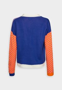 Stickad tröja med blå kropp, orange och rosa rutiga ärmar samt vit ribbad krage. Texturerad tyg med kontrasterande mönster.