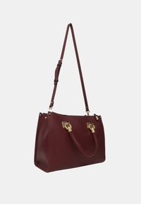 Borsa in pelle bordeaux con manici intrecciati, hardware dorato e tracolla regolabile su sfondo bianco.