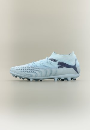 Hellblauer Fußballschuh mit schwarzem Puma-Logo, strukturiertem Obermaterial und genopptem Sohlenprofil für Spiele auf festem Untergrund.