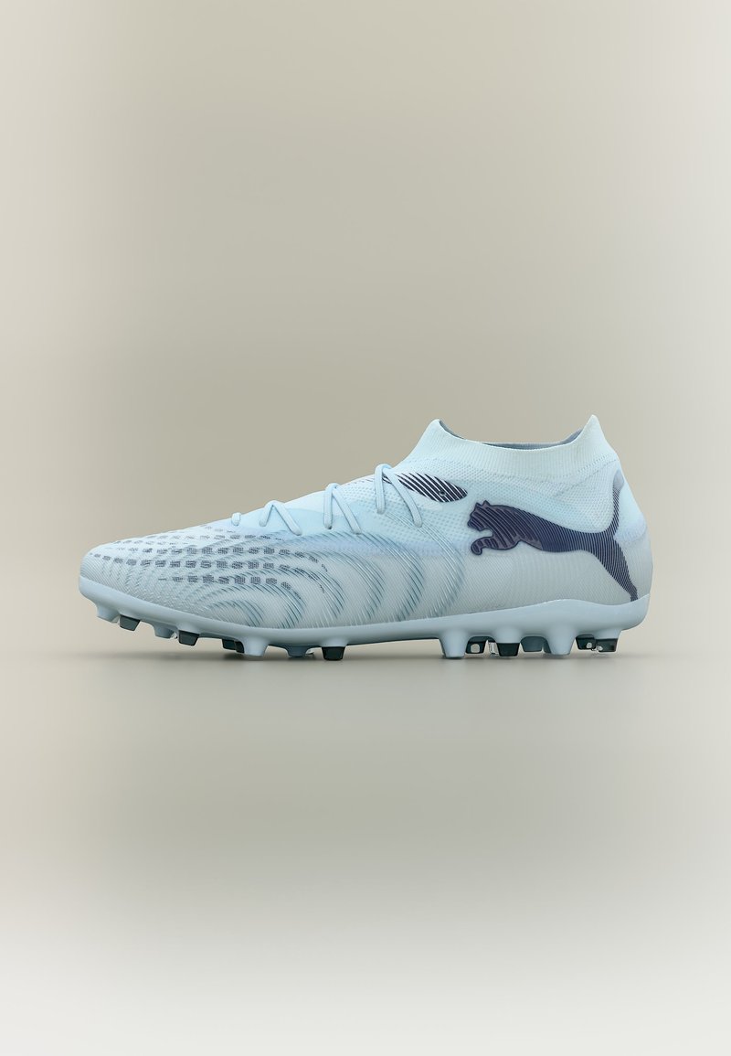 Hellblauer Fußballschuh mit schwarzem Puma-Logo, strukturiertem Obermaterial und genopptem Sohlenprofil für Spiele auf festem Untergrund.