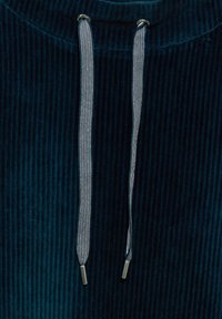Tessuto di velluto a coste blu navy con righe verticali, dotato di occhielli in tono argentato e cordini a strisce con estremità metalliche.