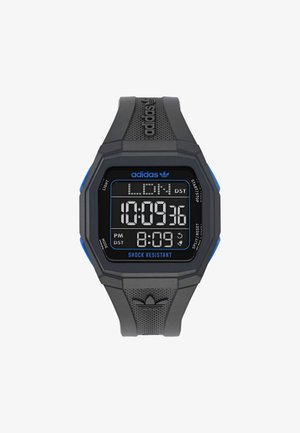 Digital wristwatch with a black rubber strap, octagonal shape, blue accents, and a digital display showing time and "SHOCK RESISTANT" text.