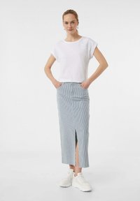 Biała bluzka z krótkim rękawem, ozdobiona haftem kwiatowym na ramieniu, zestawiona z niebieską i białą paskowaną długą spódnicą z rozcięciem z przodu. Białe trampki.