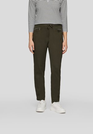 Olivgrüne tapered Jogginghosen mit vorderen Reißverschlusstaschen und verstellbarem Kordelzugbund, kombiniert mit einem schwarz-weißen gestreiften Oberteil.