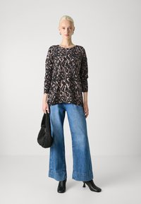 Black and pink patterned knit sweater, wide blue denim jeans, black heeled boots, and a textured black bag, displayed against a neutral background.