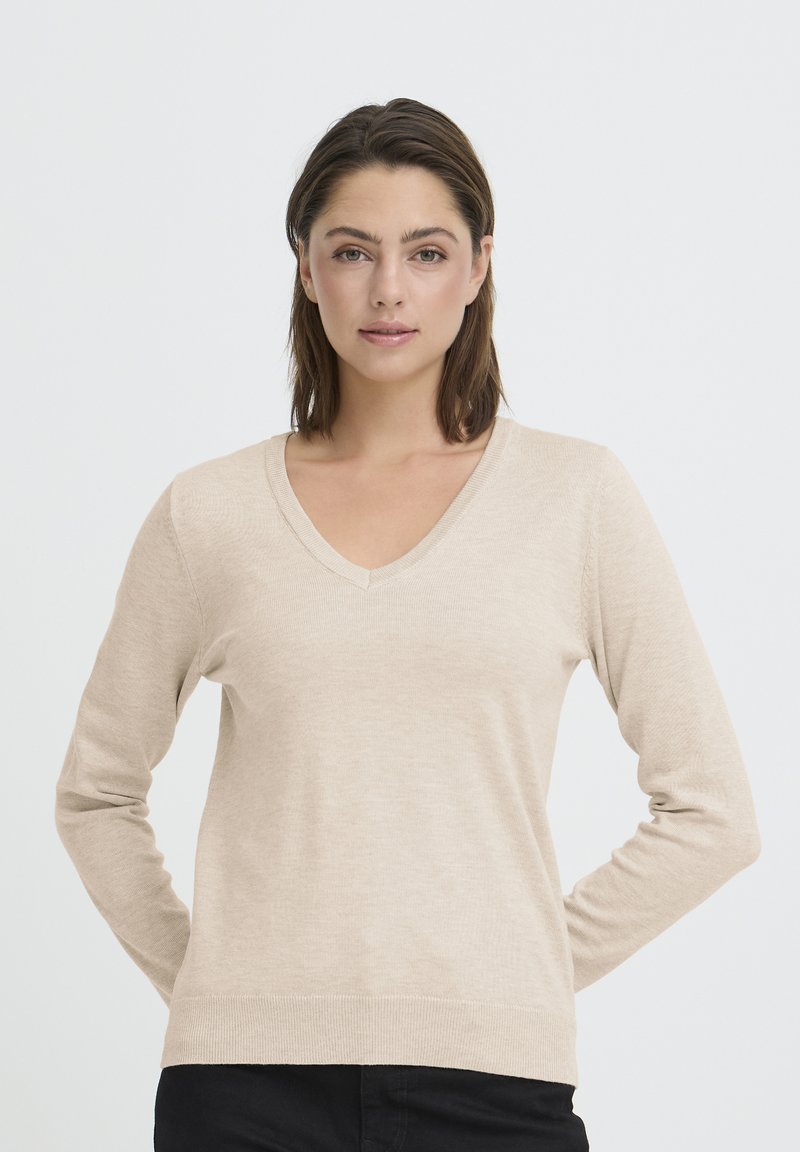 Pull beige à col en V avec manches longues, fabriqué dans un matériau lisse et léger, présentant une coupe ajustée et une texture subtile.