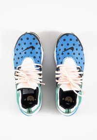 Modré a černé tenisky s puntíky, růžovými tkaničkami, bílými akcenty a zelenou oporou paty. S černým logem Nike na boku.