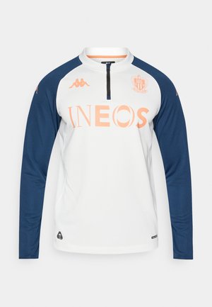 Długi top sportowy z białym korpusem, granatowymi rękawami, kołnierzem na półzamek oraz pomarańczowym logo "INEOS" na środku. Marka Kappa na rękawach.